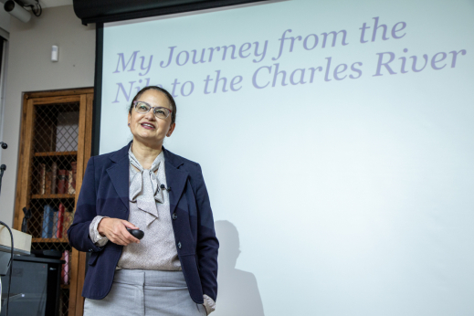 Nawal Nour stands in front of a projector screen with her presentation title, &quot;My Journey from the Nile to the Charles River.&quot;