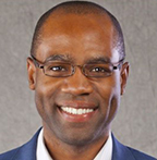 Julian Harris has very short black hair and glasses.