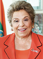 Donna Shalala has short blonde hair and is wearing an orange suit.