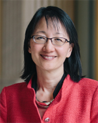 Vivian Lee has short black hair and glasses and is wearing a red jacket.