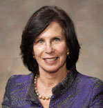 Gail Wilensky has short dark hair and is wearing a purple patterned jacket and pearl necklace.