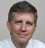 James Campbell has short brown-gray hair and is wearing a white shirt.