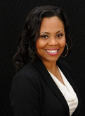 Christina Rosenthal has long black hair. She is wearing a white blouse and black blazer.
