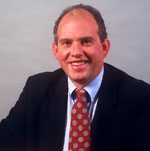 David Gifford has short dark hair and is wearing a suit with a printed red tie.