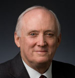 John Howe has short white hair and is wearing a suit.