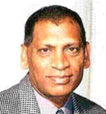 Dr. The Honorable Leslie Ramsammy has short black hair and is wearing a patterned blazer.