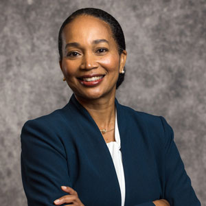 Nakela Cook has black hair tied back and is wearing a dark blue blazer and white shirt.