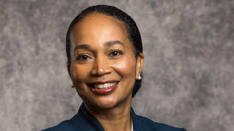 Nakela Cook has black hair tied back and is wearing a dark blue blazer and white shirt.
