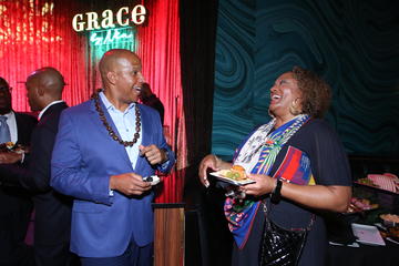 Alden Landry and Michelle Taylor laugh in conversation. The Grace by Nia neon sign is visible in the background.
