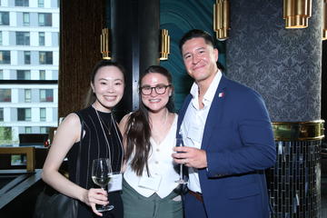 Three fellows stand by the bar at Grace by Nia. Two of them are holding wine glasses.