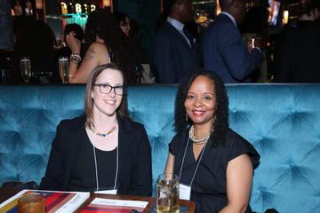 Two alumni fellows sit in a blue tufted booth at Grace by Nia.