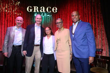 The fireside chat participants pose for a photo underneath the neon Grace By Nia sign. 