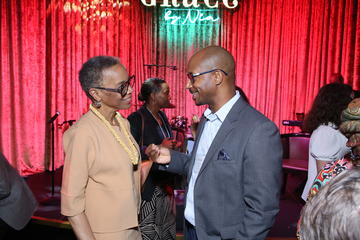Joan Reede speaks to an alumni fellow in front of the Grace By Nia stage.
