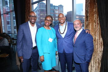 Alumni fellows stand in front of a large window in Grace By Nia. 