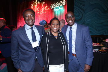 Three alumni fellows stand in front of the Grace By Nia stage.