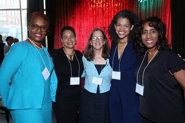 Several fellows pose by the window and stage at Grace By Nia.