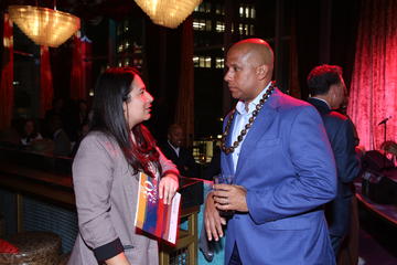 Two people speak to each other, one of them holding the event's program book.