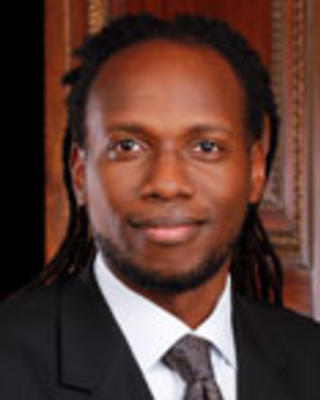 Ali Thomas has long black locs and is wearing a suit.