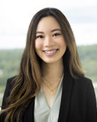 Aurelie Tran has long brown hair and is wearing a light green blouse with a black blazer.
