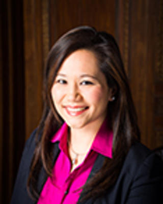 Kimberly Change has long straight black hair. She is wearing a pink shirt and black blazer.