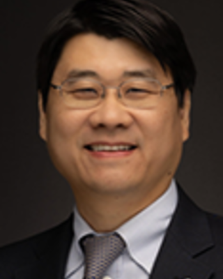 Don Lee has short black hair and glasses.