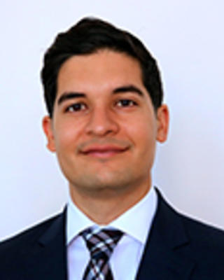 Daniel Gonzalez has short black hair and is wearing a suit.