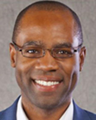 Julian Harris has very short black hair and glasses.
