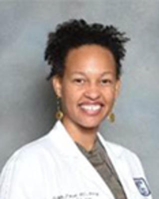 Michelle Morse has short coily black hair. She is wearing a white coat.
