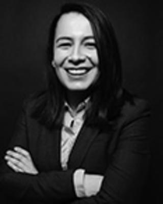 Nahiris Bahamon has long black hair. She is wearing a shirt and blazer and has her arms crossed in front of her while smiling.