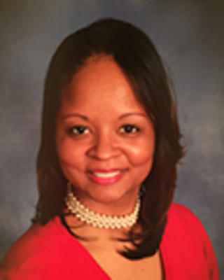 Tamiko Morgan has medium-length black hair. She is wearing a pearl choker necklace and red dress.