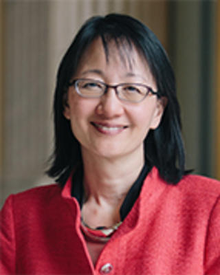 Vivian Lee has short black hair and glasses and is wearing a red jacket.