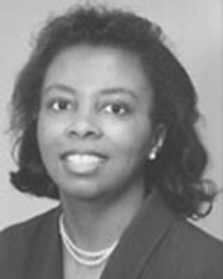 Lisa Benton has short black hair. She is wearing a necklace and black blazer.
