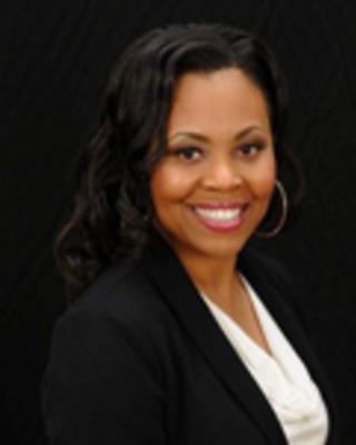 Christina Rosenthal has long black hair. She is wearing a white blouse and black blazer.