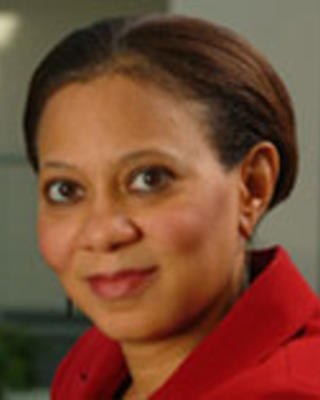Lisa Cooper has short brown hair and is wearing a red shirt.