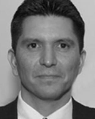 Philip DeChavez has short hair combed back and is wearing a suit.