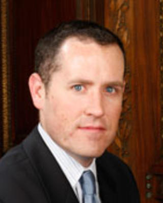 Thomas Halligan has short brown hair and is wearing a suit.