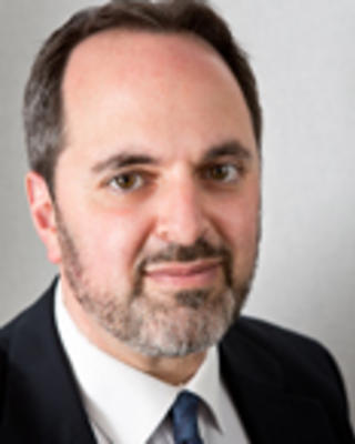 Robert Marlin has short brown hair and gray facial hair. He is wearing a suit.