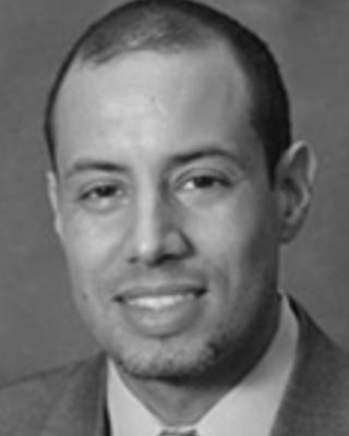 Julian Nieves has very short black hair and light facial hair.