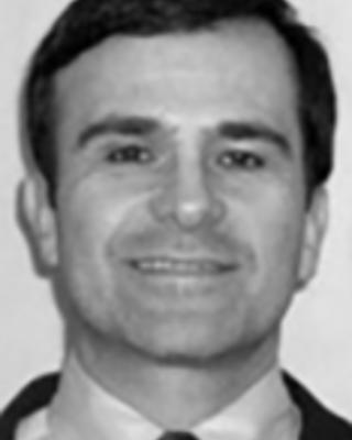 Richard Nunes has short dark hair and is wearing a suit.