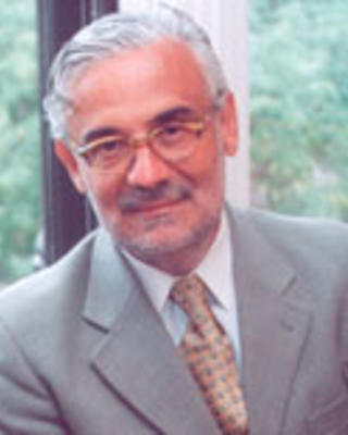 Marcelo Suárez-Orozco has short gray hair and glasses. He is wearing a gray blazer.
