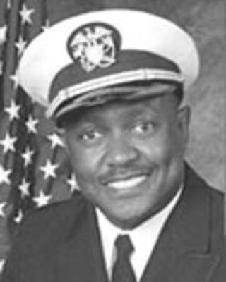 Phillip Woods is wearing an army service uniform and posed in front of an American flag.