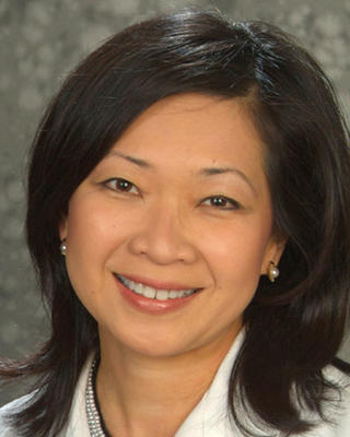 Quyen Ngo-Metger has medium length black hair. She is wearing a white coat.