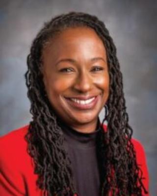 Creshelle Nash has long mini twist hair. She is wearing a black turtleneck and red jacket.