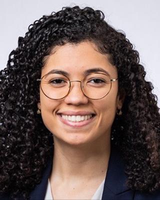 Jeslyn Rodriguez has medium length curly black hair and glasses.