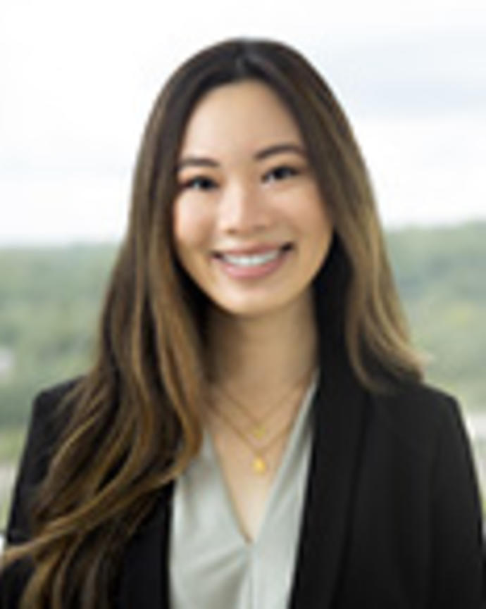 Aurelie Tran has long brown hair and is wearing a light green blouse with a black blazer.
