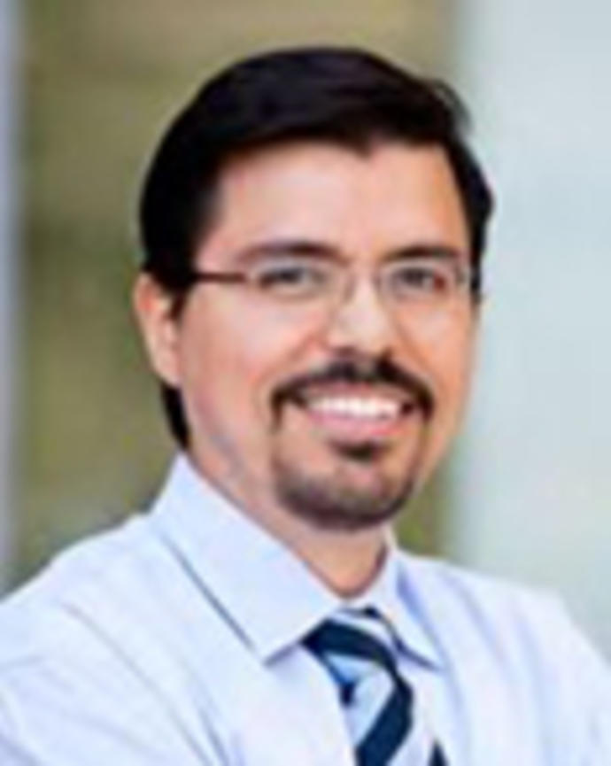Luis Castellanos has short black hair, a goatee, and moustache. He is wearing glasses.