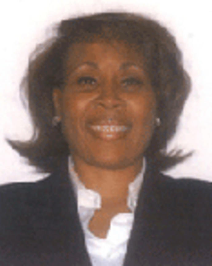 Connie Gistand has chin-length brown hair and is wearing a white shirt with a black blazer.