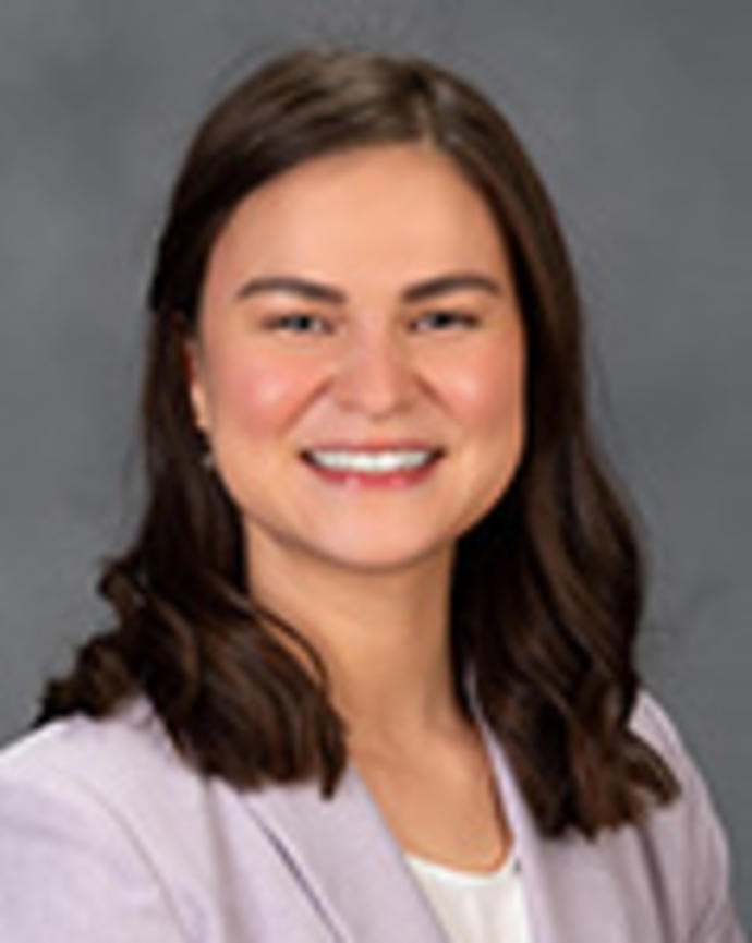 Diana Rubio has medium-length brown hair. She is wearing a white shirt and light purple blazer.