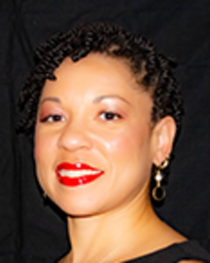 Mary Fleming has short hair twists and is wearing a sleeveless black dress.