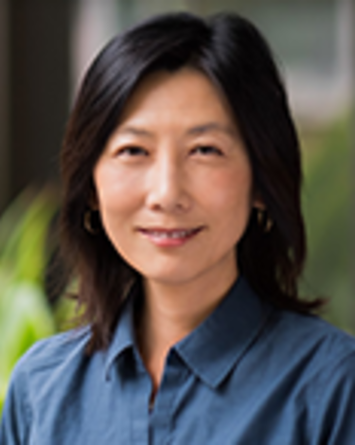Joan Jeung has shoulder-length black hair and is wearing a blue shirt.